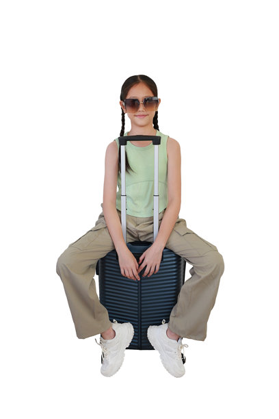 亚洲女孩坐在行李箱上，摆姿势并直视镜头，佩戴着太阳镜，背景为白色。儿童时尚与旅行概念。全身照片。图片下载