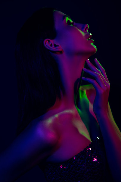 时尚年轻女性在霓虹灯下摆姿势，展示优雅的时尚与美丽，竖版照片图片下载