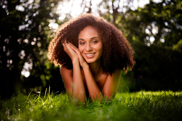 迷人可爱的女士躺在阳光明媚的草坪上，户外拍摄照片。图片下载