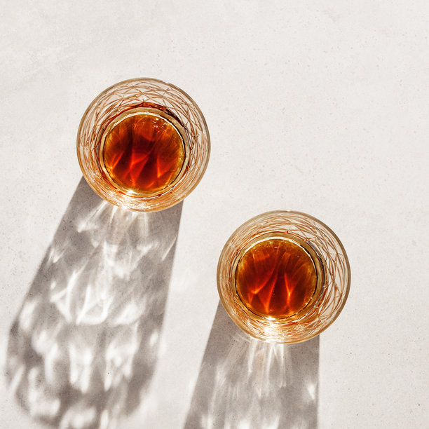 米色背景上的威士忌杯，阴影与阳光的反射，中性色调的极简风格照片，夏季静物的美学俯视图，通过水晶杯的折射与光泽，光晕效果。图片下载