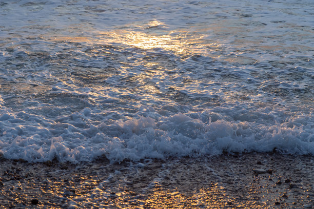 海洋或海面在日落时分的水波抽象照片，金色光调的背景图案。图片下载