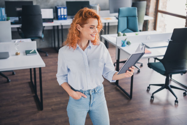 高角度视图照片，成功的年轻女商人在现代阁楼室内办公室阅读书籍和日程本图片下载