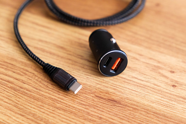 紧凑型USB C车载充电器，带可拆卸电缆，适用于快速充电设备，放置在木质表面上图片下载