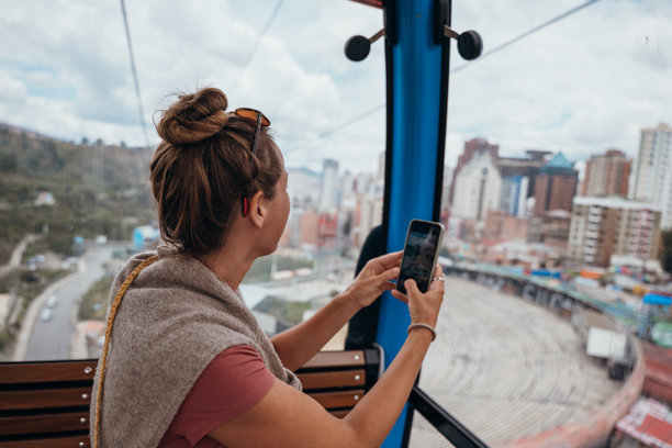 女子在缆车上拍摄俯瞰城市景观的照片图片下载
