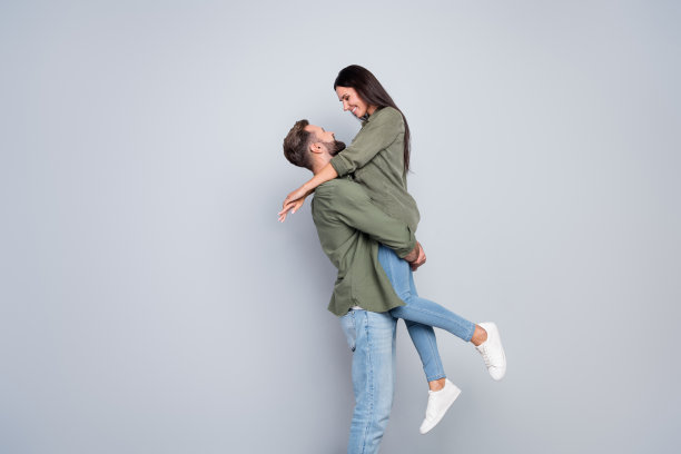 迷人的已婚女士与丈夫在灰色背景下依偎享受蜜月的侧面照片图片下载