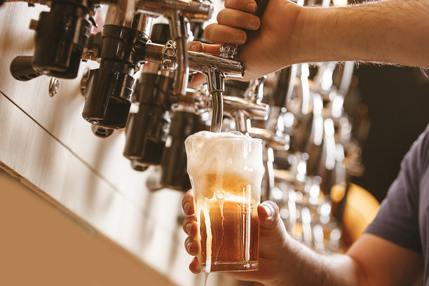 男子在酒吧从龙头倒入冰镇啤酒到杯子里图片下载