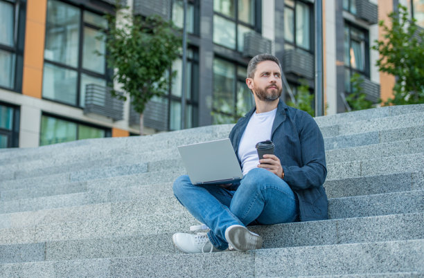 户外工作的自由职业者男士，广告。自由职业者男士与电脑的照片。图片下载