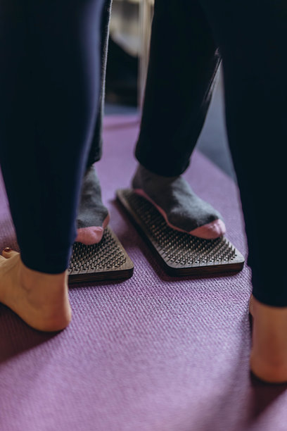 年轻女性在大自然中练习瑜伽和疗法，站在钉子板上。高质量照片图片下载