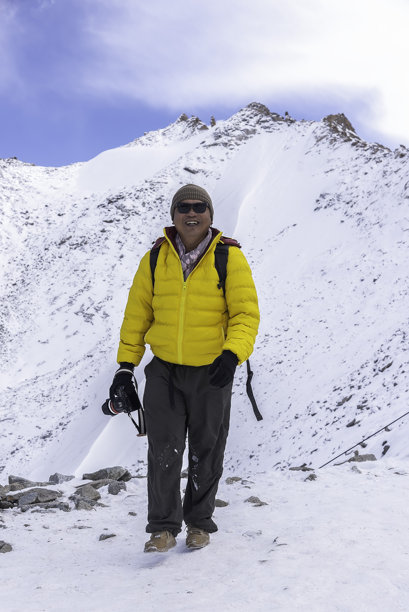 摄影师在雪山中背着背包进行徒步旅行拍摄冬季照片图片下载