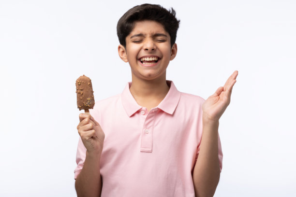 穿着红色T恤的少年男孩在白色背景下吃冰淇淋的肖像照片图片下载