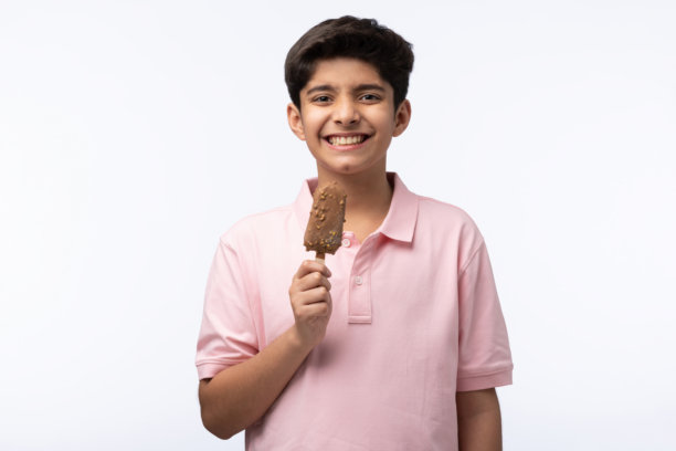 穿着红色T恤的少年男孩在白色背景下吃冰淇淋的肖像照片图片下载