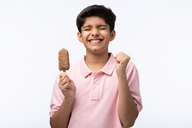 穿着红色T恤的少年男孩在白色背景下吃冰淇淋的肖像照片图片下载