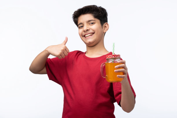 穿着红色T恤的少年男孩在白色背景下喝冷饮的肖像照片图片下载