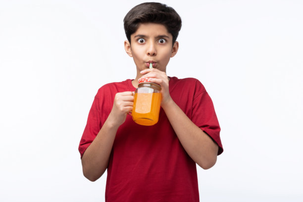 穿着红色T恤的少年男孩在白色背景下喝冷饮的肖像照片图片下载