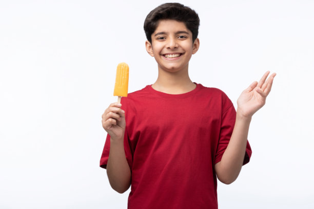 穿着红色T恤的少年男孩在白色背景下吃冰淇淋的肖像照片图片下载