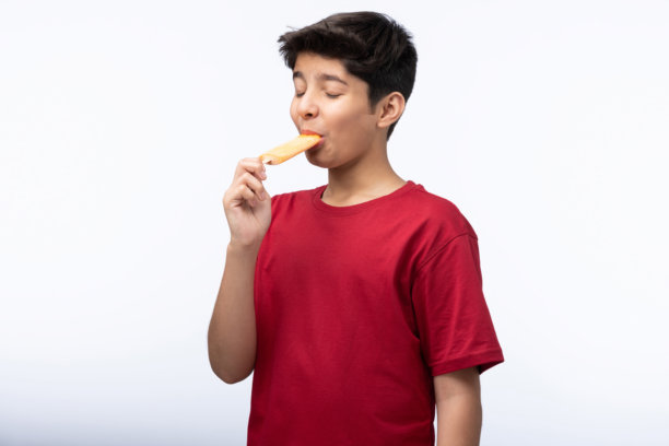 穿着红色T恤的少年男孩在白色背景下吃冰淇淋的肖像照片图片下载