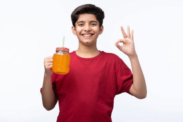 穿着红色T恤的少年男孩在白色背景下喝冷饮的肖像照片图片下载