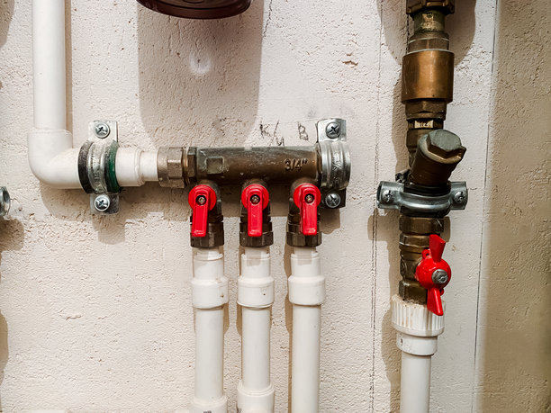 这张图片展示了一个详细的管道系统特写，包含一系列白色管道和鲜艳的红色阀门，展现了现代管道设计的复杂性。图片下载