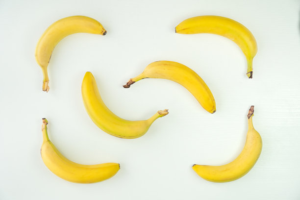 白色背景桌子上的未剥皮黄色香蕉俯视照片图片下载