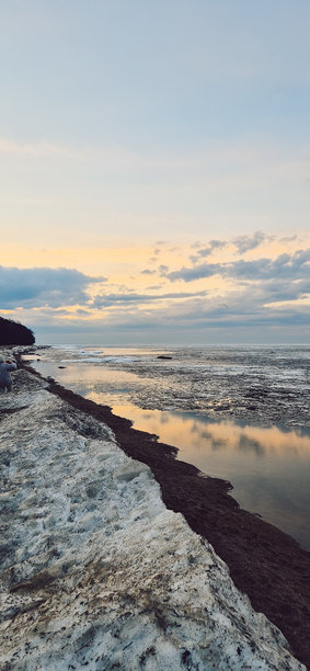 宁静的冰块在日落时分映照在平静的海洋水面上。竖版照片图片下载