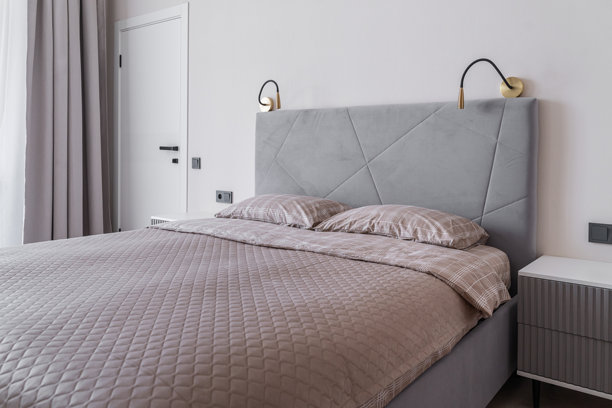 现代卧室内部，配有家具。双人床上铺有枕头和床单，床头柜。卧室内光线柔和舒适，色调宁静。时尚公寓室内。卧室照片。图片下载