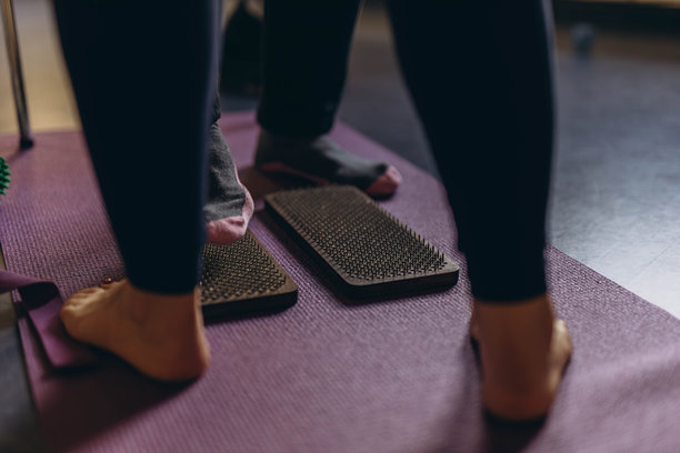 年轻女性在大自然中练习瑜伽和疗法，站在钉子板上。高质量照片图片下载