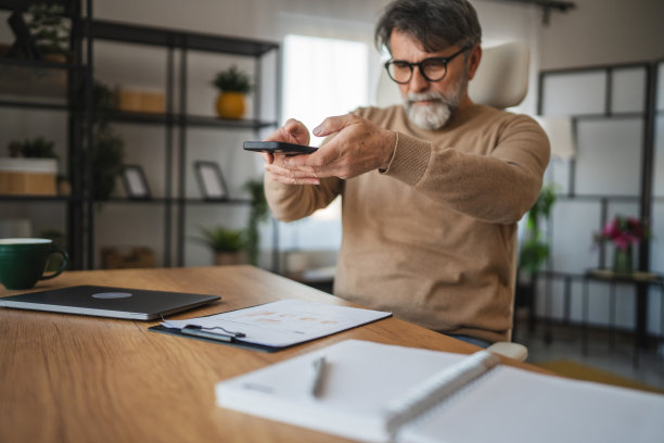成熟的老年男子用手机拍摄夹板的照片图片下载