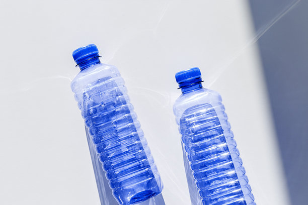 清晰的塑料水瓶，装满洁净的水，背景为白色和蓝色，特写，极简美学生活照片，俯视图，平铺，天然光，阳光阴影，光线折射效果，星形滤镜图片下载