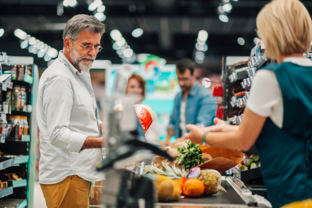 成熟顾客在超市收银台付款购买杂货图片下载