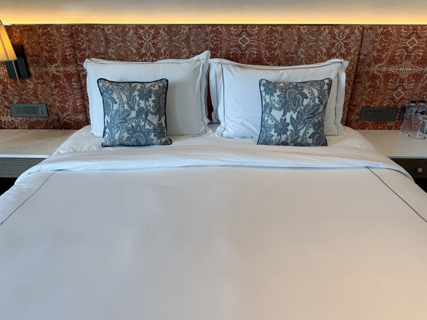 现代卧室的图片，配有条纹被子、白色枕头、散落的靠垫 / 舒适的床铺布置，优雅的被子，现代室内设计图片下载