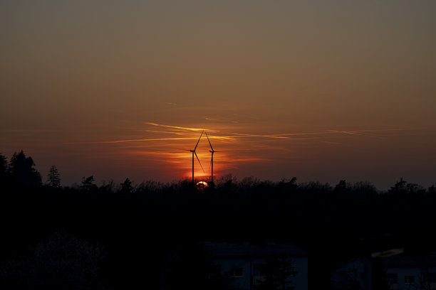 两座风力涡轮机的剪影并排矗立在橙色日落背景下的横向照片。可再生能源的生态概念。图片下载