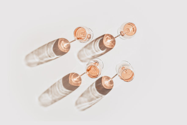 玫瑰酒杯极简风格平铺。假日美学静物照片，阳光下的酒杯俯视图，阳光投影，单色米色桃粉色柔和色调，时尚饮品背景图片下载