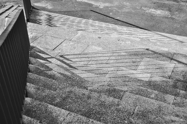 单色照片，楼梯的特写，栏杆投射在楼梯上的阴影图片下载