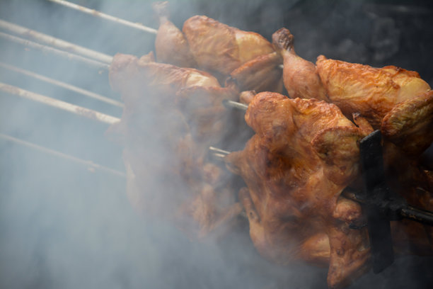 火上的鸡肉。鸡肉烧烤。餐厅中烤箱里的烤鸡，特写照片。烟熏中的烤鸡。快餐。图片下载