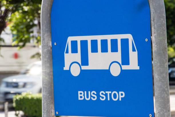 一块蓝色的板子，上面有一个公交车站的图片，背景是交通繁忙的城市。城市交通系统。图片下载