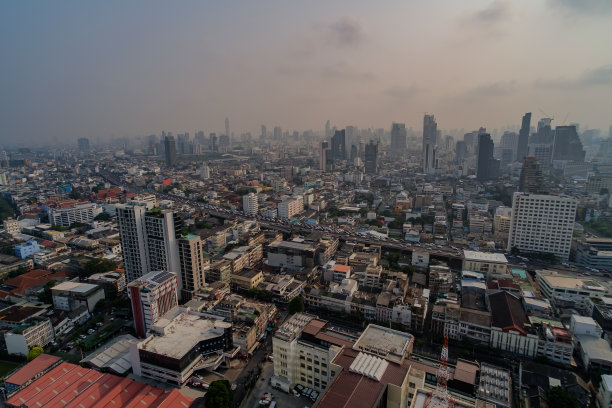 城市天际线照片展示了大城市高速公路上的交通拥堵，傍晚时分被尘雾笼罩，天空呈现出两种颜色。图片下载