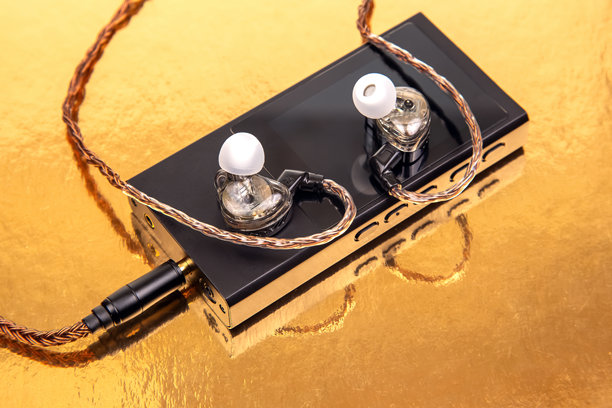 一对带编织线缆的有线耳塞放在黑色音频设备上，背景为金色。非常适合科技、音乐和音频设备主题。高分辨率库存照片。图片下载