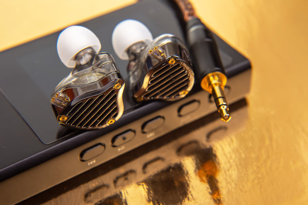 带编织线缆的有线耳塞放置在黑色音频设备上，背景为光滑的金色。非常适合音乐爱好者、科技爱好者和产品拍摄。高分辨率照片。图片下载