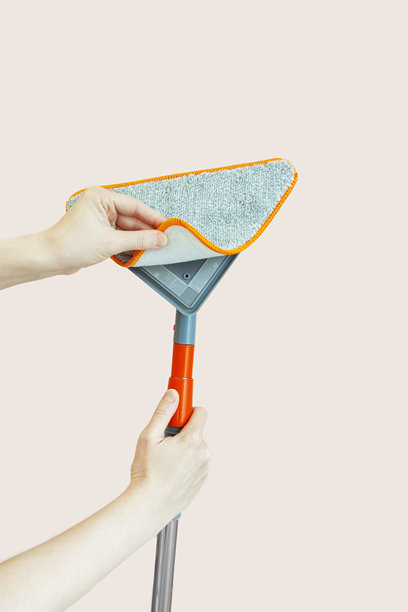 手持带有魔术贴抹布的伸缩刷的白人女性。将抹布固定在魔术贴上。米色背景。图片下载