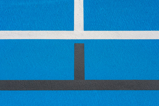 新建的户外蓝色网球场特写照片，白色线条与黑色皮克球线条相结合。图片下载
