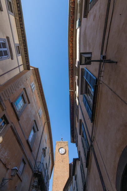 一幅风景如画的历史钟楼照片，周围环绕着乡村建筑和蔚蓝的天空。图片下载