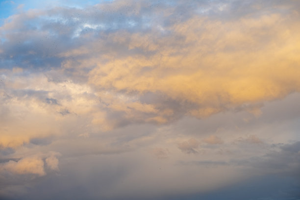 自然多云的天空，装饰性的云朵，阳光照耀下的蓝天，伴有大小不一的云朵，深色云层与金色的天空。浓厚的多云天气。非人工智能图像，真实照片。图片下载