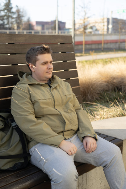 年轻的30多岁男子独自坐在秋天公园的长椅上，思考生活。在城市中独自度过时光。高质量照片。图片下载