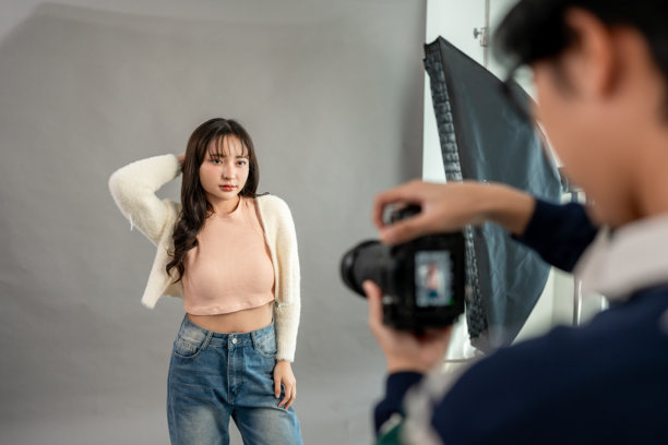 亚洲女性模特在摄影工作室被摄影师拍摄。吸引人的专业摄影师为年轻女孩拍摄美丽的照片，背景用于制作广告图像。图片下载