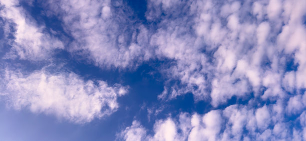 阳光明媚的日子，蓝天上飘着蓬松的白云。适用于网站展示、横幅和海报的优质天空背景照片。图片下载