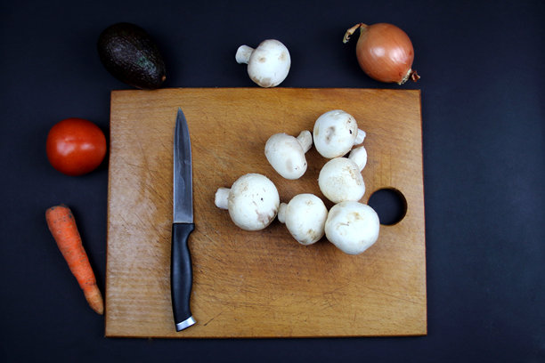 概念照片健康饮食。板上有一把刀和一堆蘑菇，板的周围摆放着蔬菜。图片下载