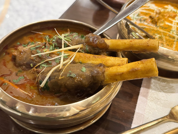 马萨拉罗根咖喱羊肉饺子的图片 / 奢华的印度美食盛放在金色盘子里 / 在印度餐厅提供的美味嫩滑羊肉菜肴图片下载