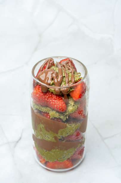 迪拜巧克力草莓杯，配有卡塔伊菲、开心果酱、牛奶巧克力和新鲜草莓。俯视图，竖版照片。街头美食甜点和糖果。文本留白。图片下载