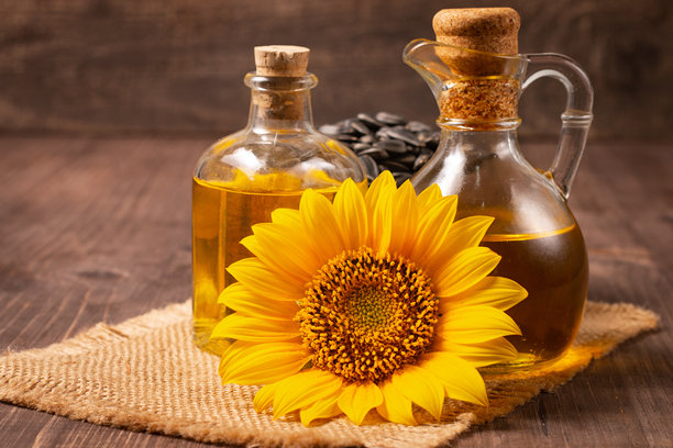 向日葵油的特写照片，背景为木质表面，旁边有种子。生物和有机产品概念。图片下载