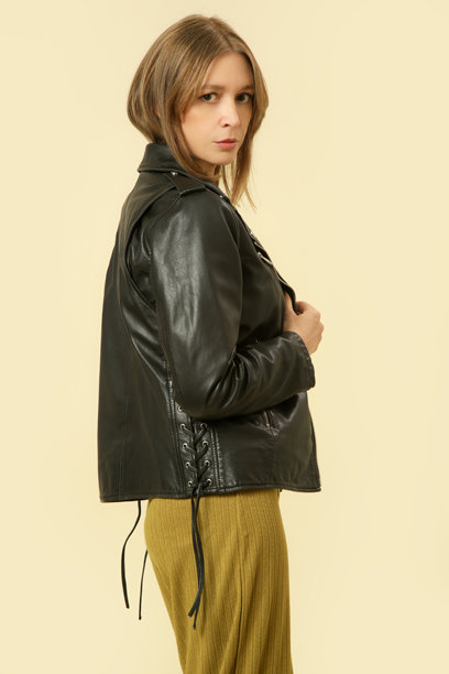 女性模特穿着基础舒适的牛油果绿色针织套装，搭配黑色皮革摩托夹克的工作室照片，秋冬时尚系列。图片下载